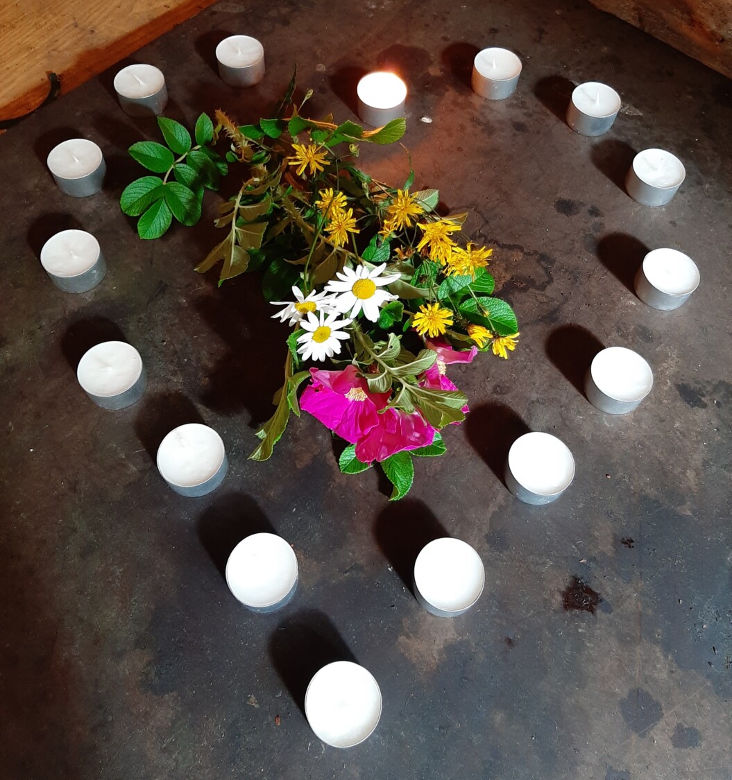 Tuikkukynttilöistä muodostettu sydän, jonka keskellä luonnonkukkia