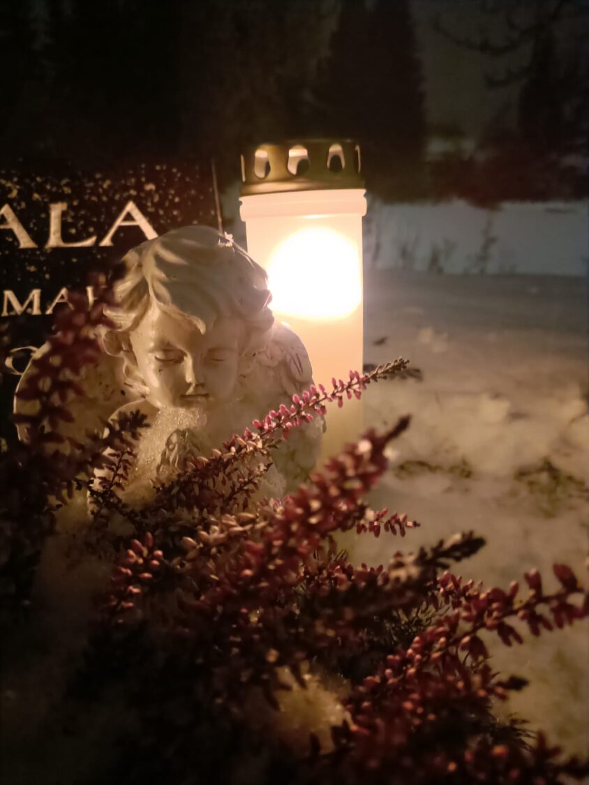 Enkelipatsaus ja hautakynttilä lumisella haudalla
