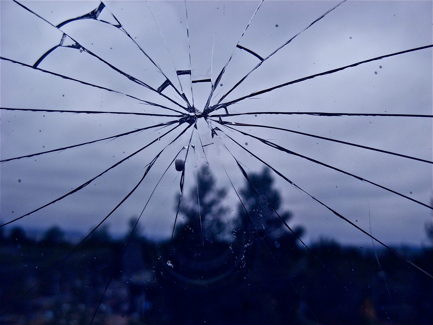 Murtuma lasissa ja taustalla tummaa metsää